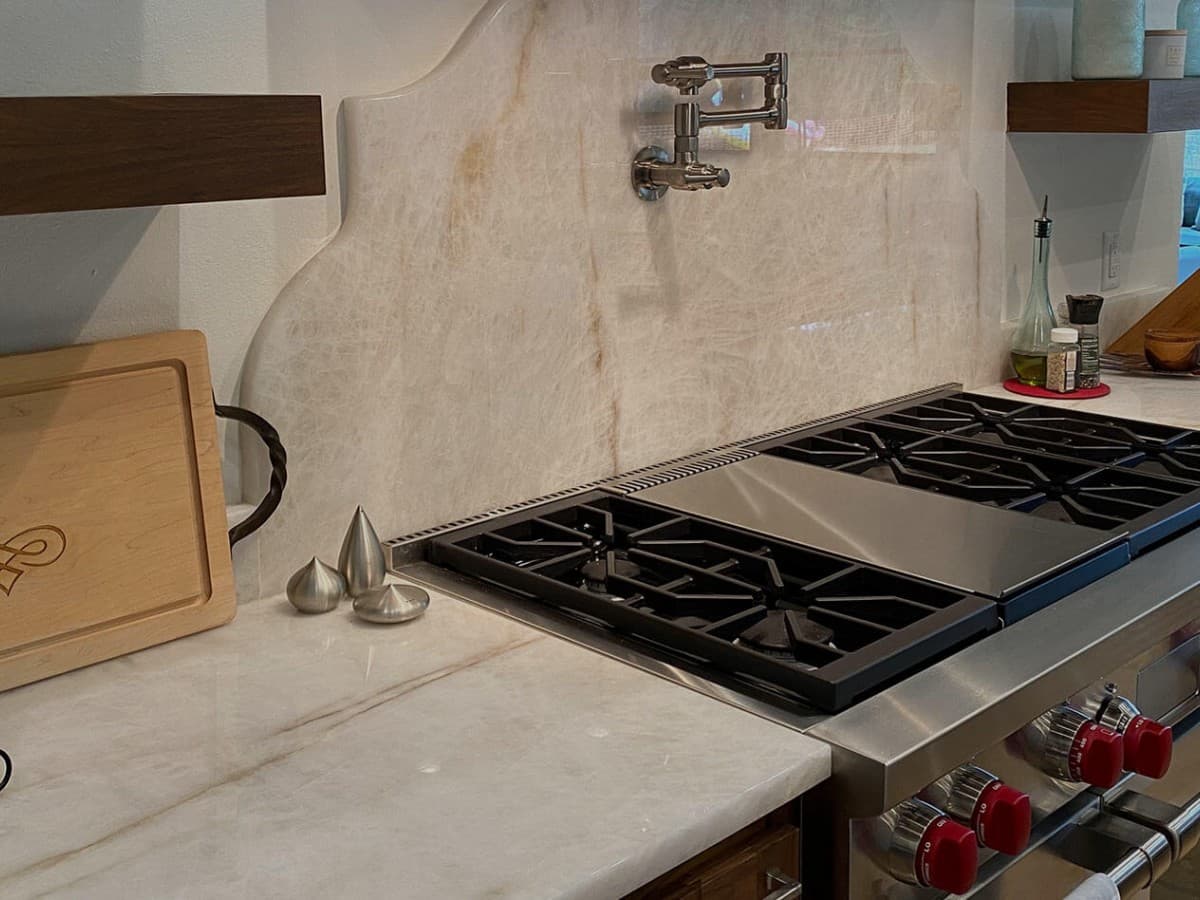 Finished kitchen range with pale stone counters and a full-height stone splash