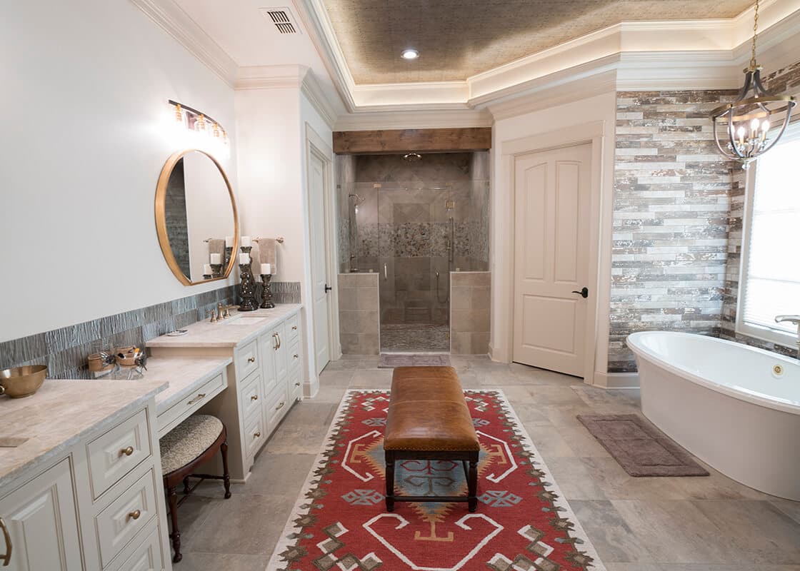Finished primary bathroom with a tiled shower, vanity, and coordinated stone details