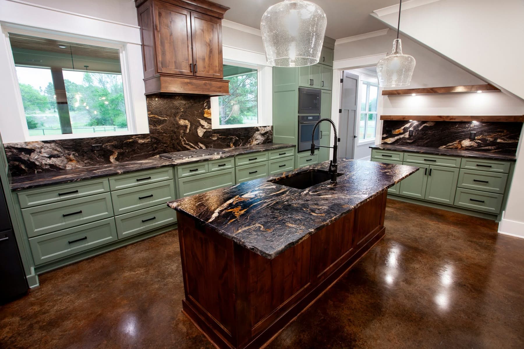 Finished kitchen with dark natural stone counters, full-height splashes, and a large island