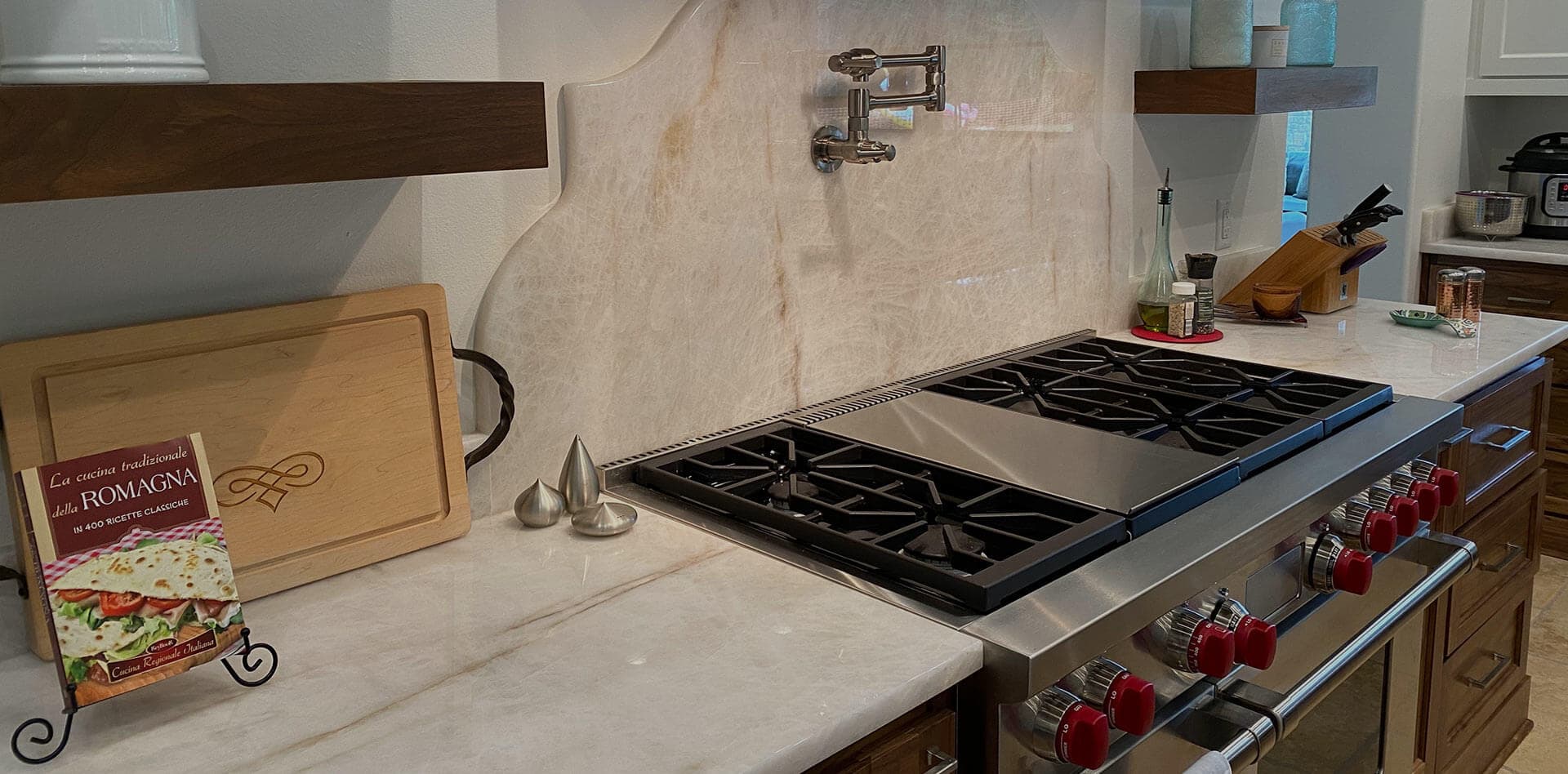 Light natural stone countertop and full-height splash fitted around a professional range