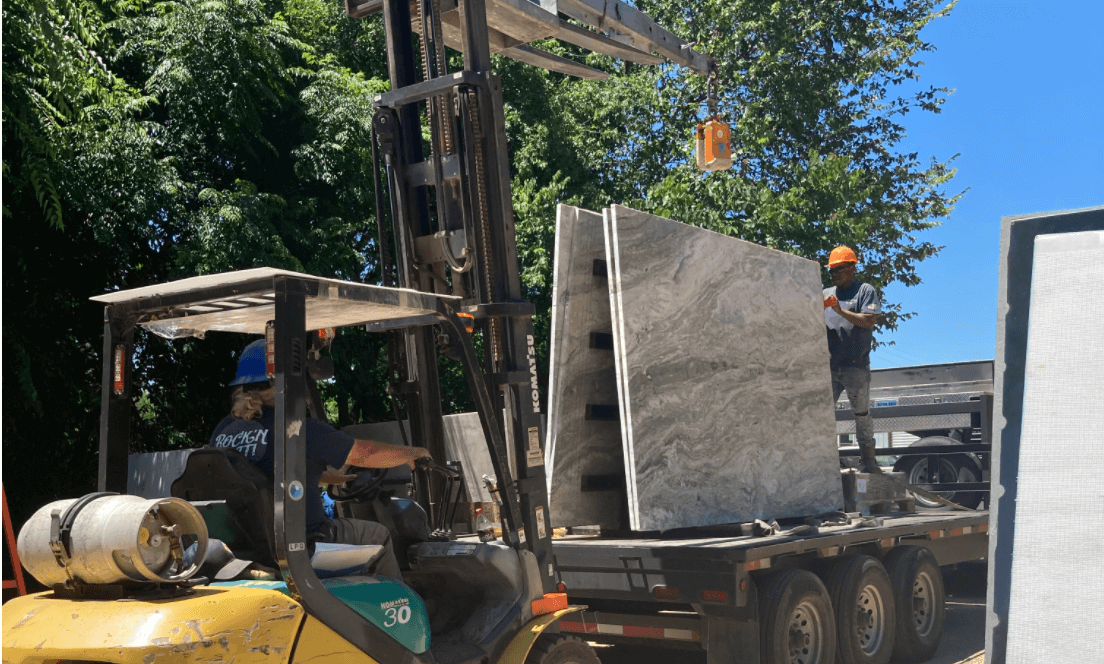 Granite Division crew unloading full stone slabs into the Tyler yard with a forklift